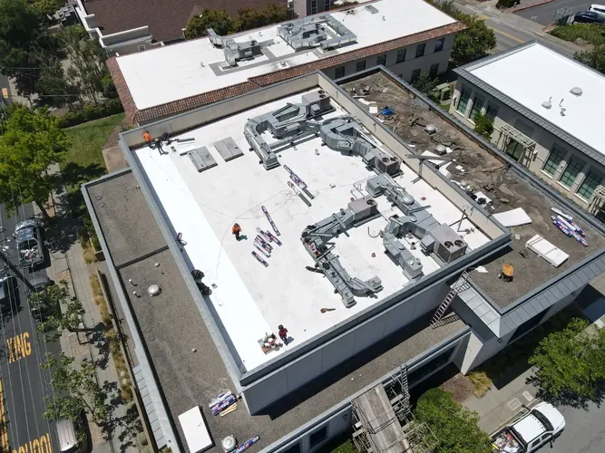Aerial view of a commercial flat roof in San Francisco with Apollo Roofing crew and HVAC units visible during repair work