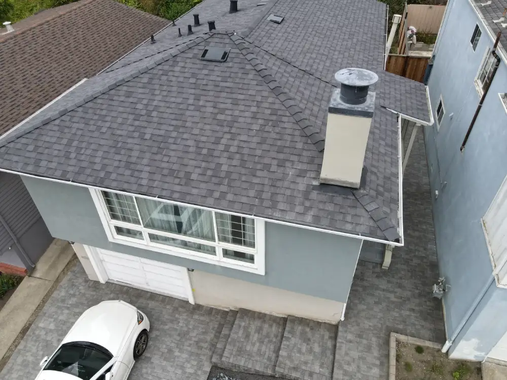 Top view of a modern home featuring gray shingle roofing and a large chimney
