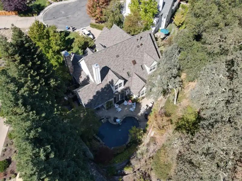 Novato residence in wooded terrain showing signs of wind-related roof damage
